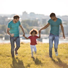 two-fathers-with-daughter-running-outside