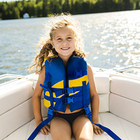 Girl sitting on boat wearing a swim vest