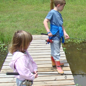 a young boy and girl stand on dock using best fishing rod and reel combo for beginners