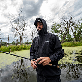 man fishing on a river on a cloudy day with a rain jacket on